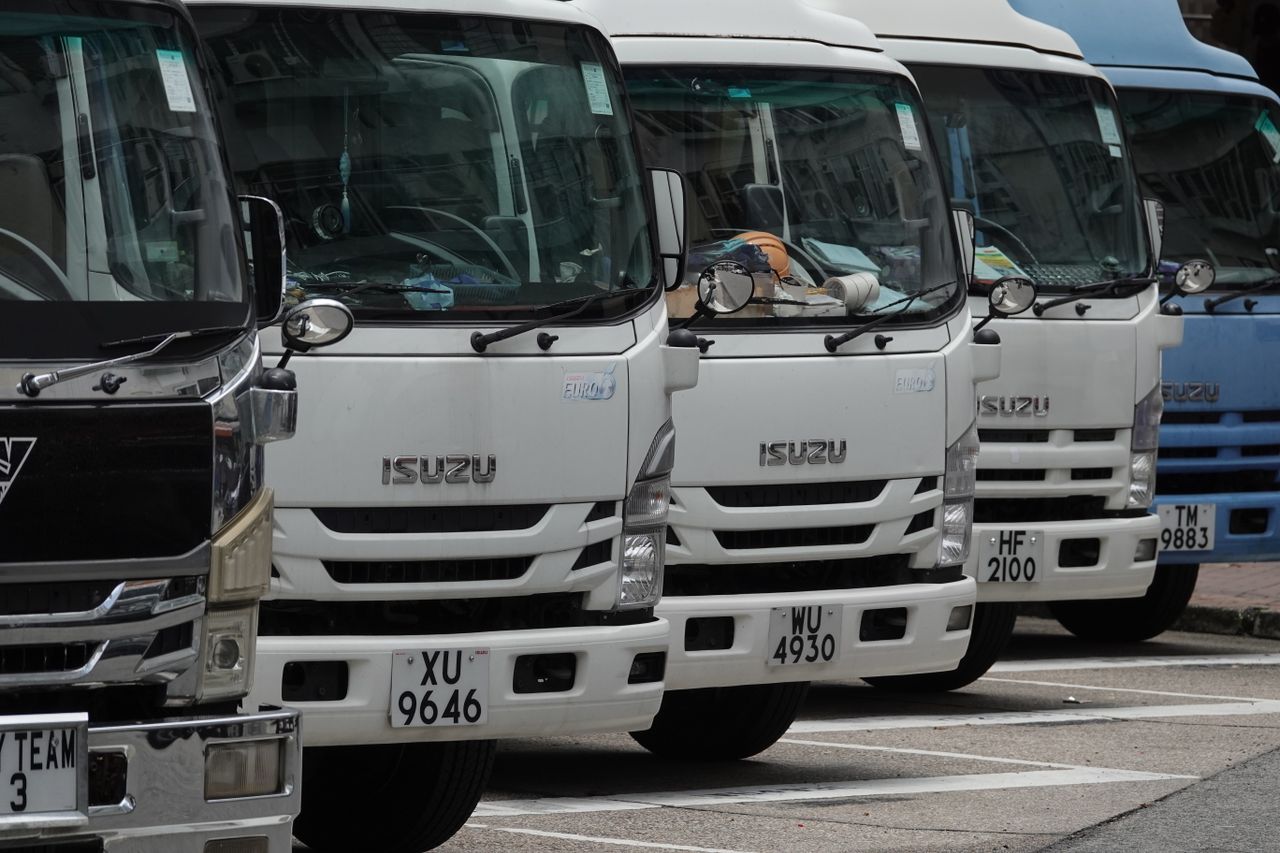 Parked Isuzu trucks lined up in the city, ready for delivery. Ideal for transport and logistics themes.