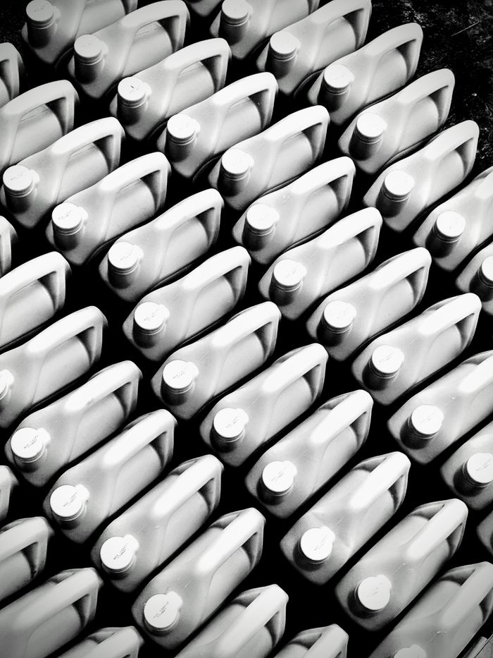 Patterned arrangement of plastic bottles viewed from above in black and white.